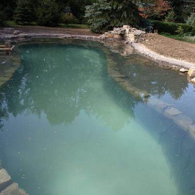 In dem noch frisch mit Wasser befüllten Teich ist deutlich die Abrenzung zwischen Badezone und späterem Pflanzbereich erkennbar